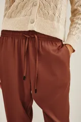 Pantalon estilo babucha color mostaza, con cintura elástica y cordón de ajuste. Presenta bolsillos diagonales en el frente y corte ligeramente ajustado hacia los tobillos.