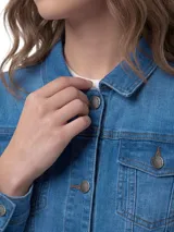 Chaqueta de jean clásica en color azul índigo, con cierre frontal de botones metálicos, cuello camisero, bolsillos superiores con solapa y botones, y bolsillos laterales.