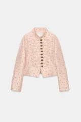 Blazer entallada de cuello alto y manga larga, en color rosado con estampado de flores amarillas. Cuenta con detalle de pasamanería en el delantero y cierre frontal con botones metálicos dorados.