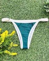 Conjunto de bikini verde esmeralda con ribetes blancos, compuesto por un corpiño triangular fijo con abertura para agregar tazas soft y una bombacha colaless regulable.