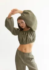 Blusa corta color salmón, con escote recto con elástico, mangas largas abullonadas con elástico en los puños y corte crop.