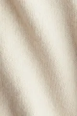 Buzo oversized de punto suave, con cuello en V, hombros caídos y terminaciones acanaladas en cuello, puños y bajo.