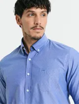 Camisa de manga larga en color azul, con cuello abotonado y bolsillo frontal en el pecho.
