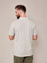 Remera polo blanca de manga corta, con detalles en azul marino en el cuello y los puños, y el logo bordado en el pecho.