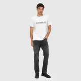 Remera blanca de corte regular con cuello redondo y mangas cortas. Presenta un estampado frontal con la frase 'BLACK IN BLACK' en color negro.