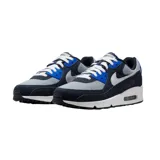 Championes Nike Air Max 90 SE, con capellada gris y detalles en azul marino y azul eléctrico. Presentan el logo de Nike en color plateado y suela blanca con cámara de aire visible.