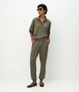 Pantalón jogger color verde oliva, con cintura elástica ajustable mediante lazo bicolor y puños ajustados en los tobillos. Presenta un corte holgado y cómodo.
