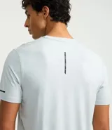 Remera deportiva de hombre con tecnología dry fit, cuello redondo y manga corta. Presenta un diseño liso en color beige con una pequeña etiqueta decorativa en el dobladillo.