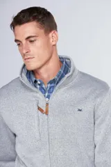Campera deportiva de tejido tipo polar en color gris jaspeado, con cuello alto, cierre frontal completo, bolsillos laterales y bolsillo en el pecho con cierre. Presenta detalles en cuero sintético y logo bordado en el pecho.