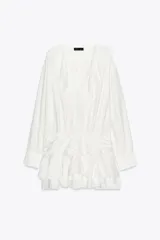 Vestido corto blanco de escote en V y manga larga con puños abotonados. Presenta volantes con bordados de encaje en el cuello, escote y falda. Cierre lateral con cremallera oculta.