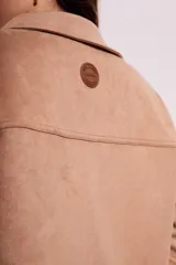 Sobrecamisa negra de estilo shacket, confeccionada en tejido de gamuza sintética. Presenta cuello camisero, cierre frontal de botones y dos bolsillos de parche con solapa en el pecho. El calce es oversize y las mangas son largas.