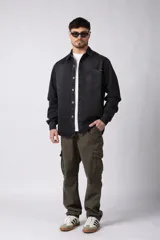 Chaqueta de jean negro desgastado, de corte recto, con cuello clásico, cierre frontal con botones y bolsillo en el pecho. Confeccionada en denim de algodón de 12 onzas.