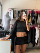 Top negro de corte crop con mangas anchas estilo murciélago y diseño holgado.