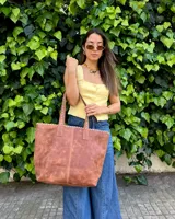 Bolso tipo tote bag color suela, confeccionado artesanalmente en cuero, con costuras visibles decorativas en los bordes y asas de hombro.
