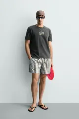 Camiseta de corte relajado con efecto lavado, cuello redondo y manga corta. Presenta estampados con textos en contraste en el frente.