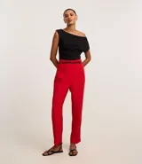 Pantalón de sastrería corte carrot, color rojo, con cintura alta, pliegues frontales y cinturón fino incluido con hebilla metálica.