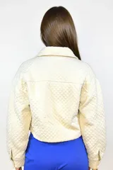 Campera corta con textura capitonada, cierre frontal con botones, cuello clásico, bolsillos frontales con solapa y elástico en la cintura y puños.