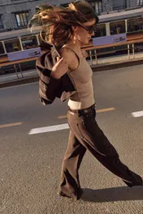 Chaqueta corta de color marrón oscuro, con cuello de solapa, manga larga con trabillas en los puños, bolsillos delanteros con solapa y cierre frontal con botones.