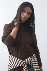 Polera de tejido de punto color marrón, con cuello alto y diseño de textura con relieves y trenzas. Posee mangas largas con puños acanalados.