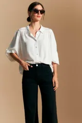 Jean azul oscuro de corte wide leg, con tiro alto, bolsillos frontales tipo parche y bajo deshilachado.