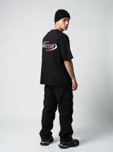 Remera negra de algodón con corte oversize y estampado frontal con la palabra "Blessed" en blanco y "by God" en rojo.