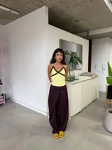 Pantalón de corte amplio y relajado en color uva, con diseño de solapas cruzadas en la cintura y cierre frontal. Presenta una silueta holgada y fluida.