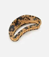 Pinza para el pelo con forma curva y diseño de carey (tortuga), combinando tonos beige y negro. Posee un mecanismo de sujeción interno metálico de color dorado.