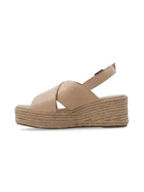 Sandalia de plataforma tipo yute con tiras cruzadas de cuero en color beige, y tira ajustable al talón con hebilla metálica.