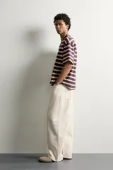 Camiseta de corte relaxed fit con diseño de rayas horizontales en tonos morado, amarillo y blanco. Presenta cuello redondo y mangas cortas.