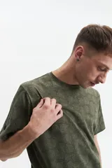 Remera verde militar con estampado de hojas en tono más oscuro, de manga corta, cuello redondo y corte regular.