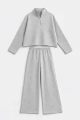 Conjunto de dos piezas en tejido de punto acanalado color gris. Incluye un buzo de corte cropped con cuello alto y cierre frontal, y un pantalón de corte recto con cintura elástica.