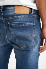 Pantalón de jean azul de corte ajustado con roturas en las rodillas.