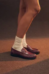 Mocasin de cuero vacuno con grabado tipo croco, color negro, con suela de goma y taco bajo.