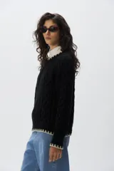 Sweater de punto de mohair color beige, con cuello redondo, mangas largas y detalles de terminación en color negro en el cuello, puños y ruedo.