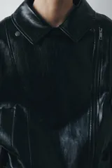 Chaqueta de estilo biker confeccionada en tejido efecto piel con acabado brillante. Presenta cuello con solapas, cierre frontal con cremallera y botones, bolsillos delanteros y bajo ajustable con trabillas y hebilla metálica.