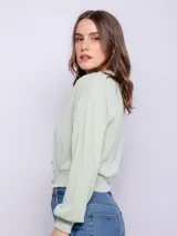 Cárdigan corto color beige, de manga larga y escote en V. Tiene cuatro botones brillantes.