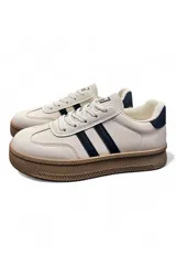 Championes deportivos de plataforma color beige con dos rayas negras laterales, suela de goma marrón y detalles en azul oscuro en el talón.