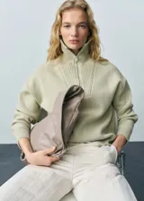 Jersey de punto de lana con cuello alto y cierre de cremallera frontal. Presenta un diseño oversize con mangas largas y terminaciones en canalé.