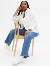 Camisa oversize blanca de popelina con cuello clásico, cierre frontal con botones y mangas largas con puños abotonados.