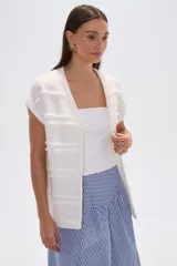 Poncho color marfil con diseño de flecos horizontales y cuello redondo.