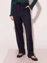 Pantalón de vestir azul marino a rayas verticales blancas, confeccionado en lana sastrera, con cintura sastrera, botas con elástico y tancas para regular.