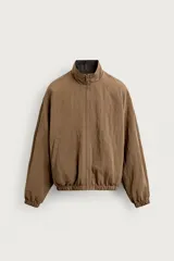 Cazadora bomber reversible de corte relaxed fit, color marrón oscuro, con cuello alto, cierre frontal de cremallera, bolsillos laterales de vivo y acabados elásticos en puños y dobladillo.