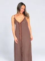Vestido maxi de lino color blanco, con escote en V, tirantes finos regulables y detalles de flecos en el frente.