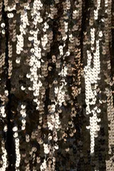 Pantalón de tiro alto confeccionado en malla revestida de lentejuelas brillantes. Presenta un corte bootcut y cuenta con forro interior de punto para mayor comodidad.