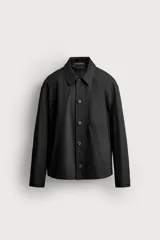 Sobrecamisa negra de corte relaxed fit, confeccionada en tejido de algodón con elasticidad. Cuenta con cuello solapa, manga larga con puño abotonado, bolsillos de vivo en la cadera y cierre frontal de botonadura.