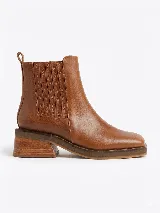 Bota tipo chelsea de cuero color suela, con paneles elásticos laterales, puntera cuadrada y suela de goma con taco de madera de diseño geométrico.