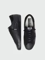 Zapatillas Golden Goose Super-Star de hombre, confeccionadas en napa y gamuza negra, con el diseño característico de la estrella en el lateral, suela de goma y acabado desgastado.