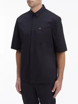 Camisa negra de manga corta con corte boxy, cuello en punta, bolsillo de parche en el pecho y logo CK bordado.