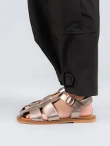 Sandalias tipo pescador con diseño de tiras anchas entrelazadas, confeccionadas en cuero color plateado. Presentan cierre mediante hebilla metálica lateral, plantilla de cuero y suela plana de goma.