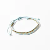 Pulsera tejida con hilo celeste y cuentas doradas y celestes.